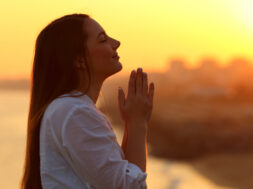 Profile of a woman praying at sunset